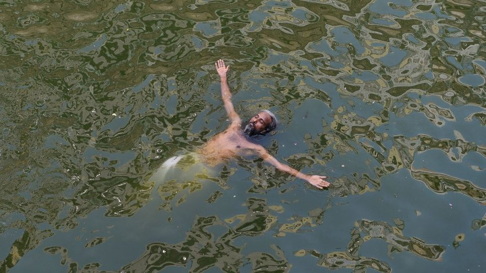 An Indian man cools off in a 'baoli' or step-well at the Nizamuddin Dargah in New Delhi