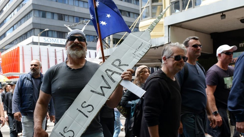 'This is a war': A protester holds up a needle sign in Melbourne, Australia