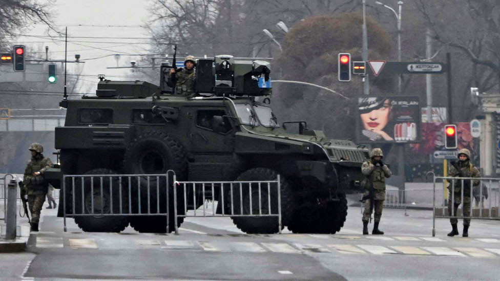 Kazakh service members stand guard at a checkpoint following the protests triggered by fuel price increase in Almaty on 7 January