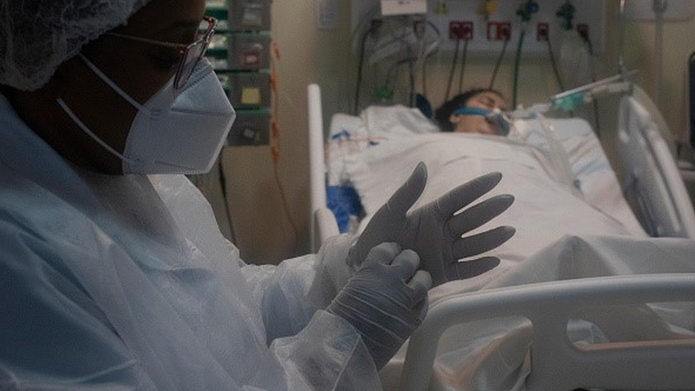 A healthcare professional takes care of a patient who is on a respirator