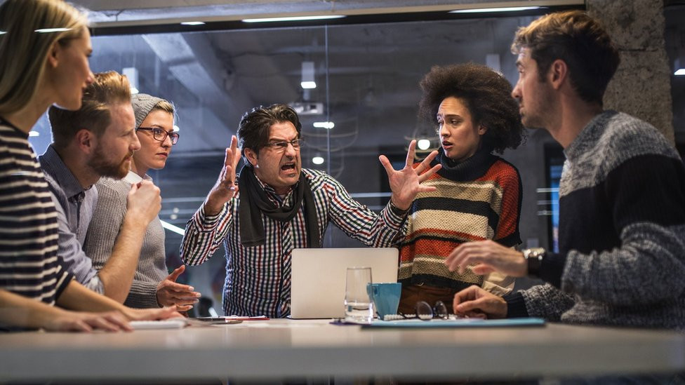 A manager shouting with his team during a meeting