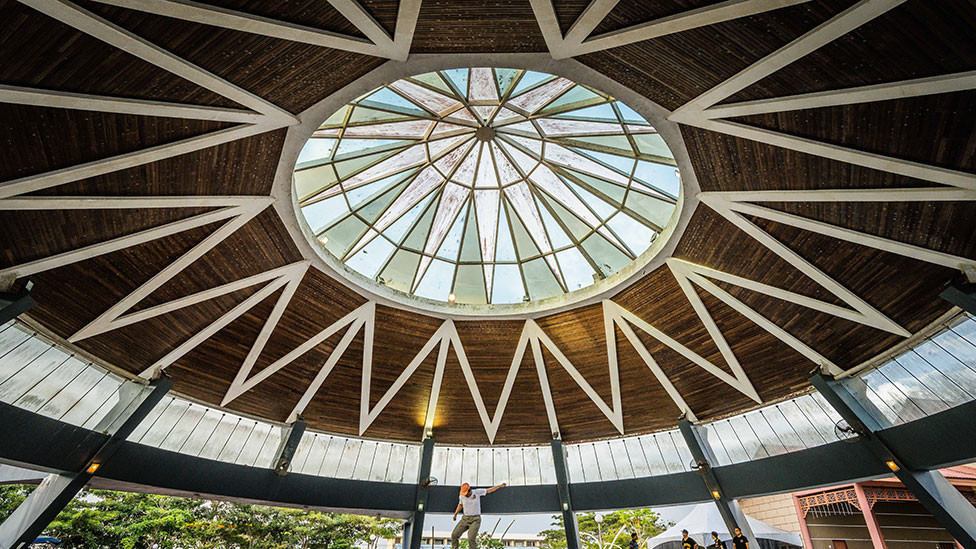 The large roof of a building in Kuching, Malaysia, with a skateboarder beneath