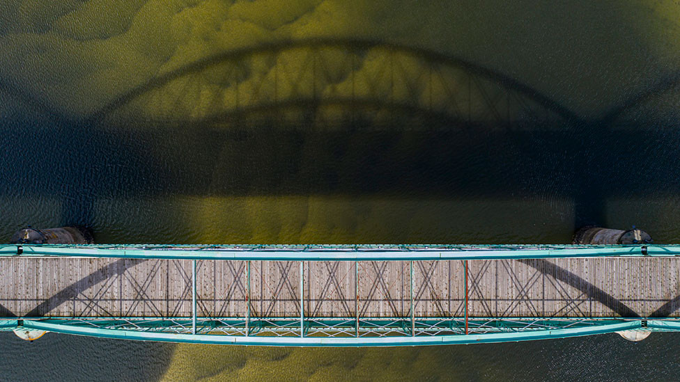 A low sun casts the shadow of a bridge onto water in Alicante, Spain