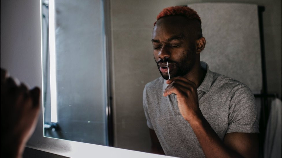 A man swabbing his nose during a lateral flow test at home