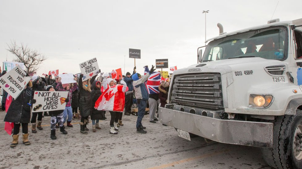 A truck is greeted as it passes by some of those who gathered to show support for the cross country truck convoy.
