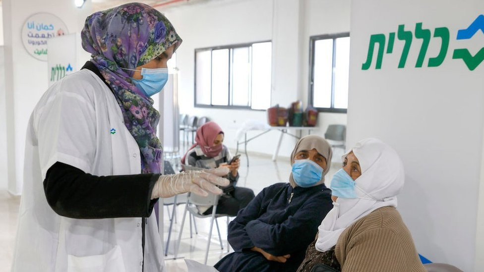 A healthcare worker speaks to an Arab Israeli woman before giving her a Covid-19 vaccine in Umm al-Fahm, northern Israel (4 January 2021)