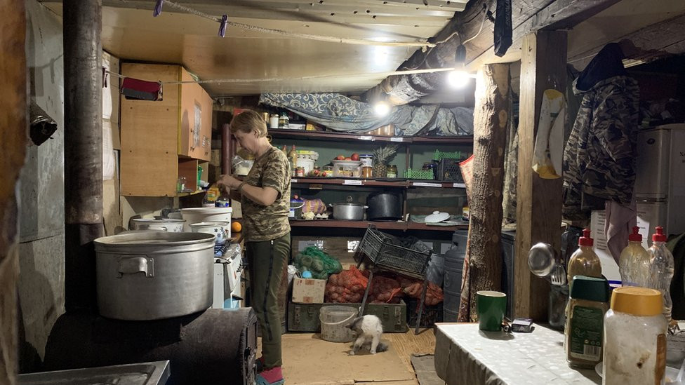 A Ukrainian soldier prepares food in a makeshift kitchen near the front lines