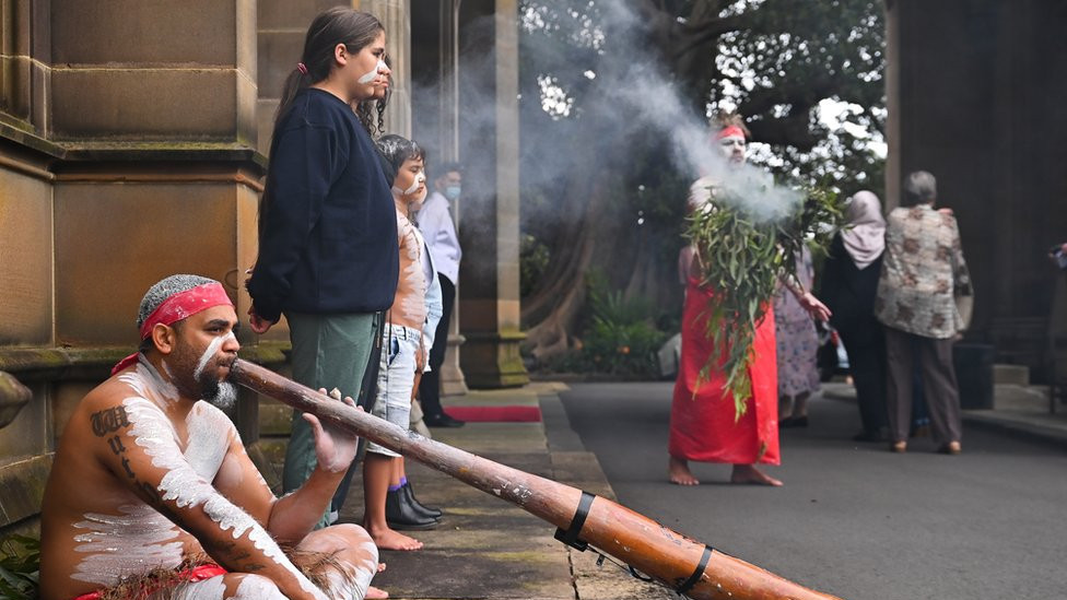 Celebrations of the accession in Sydney, Australia, including an Aboriginal smoking ceremony and man playing a didgeridoo