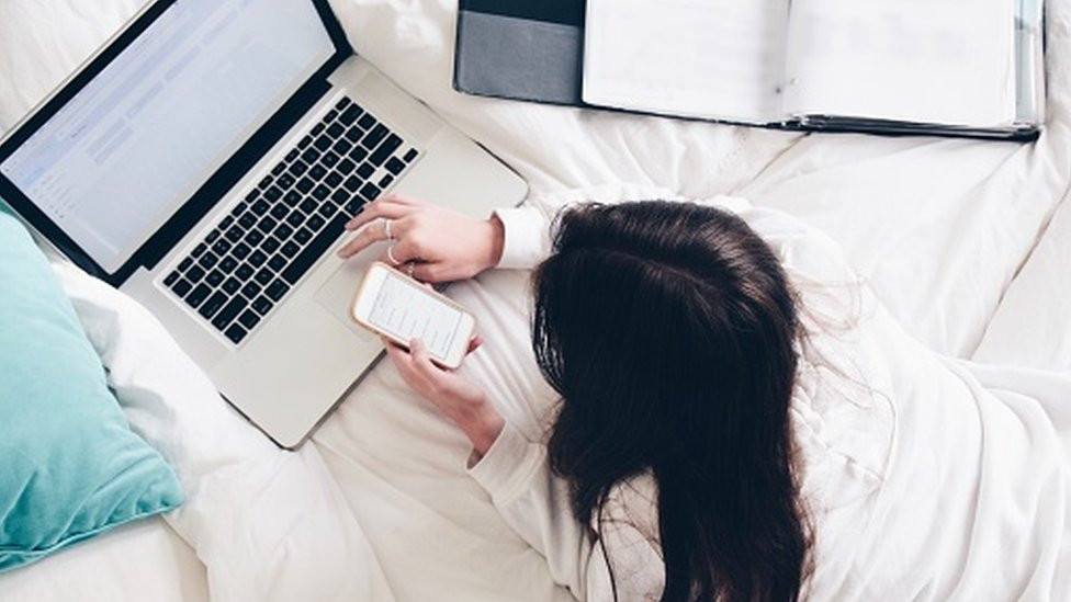 Girl on bed looking at a computer