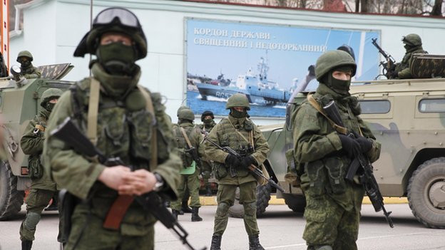 Armed servicemen wait near Russian army vehicles outside a Ukrainian border guard post in the Crimean town of Balaclava, March 1, 2014.