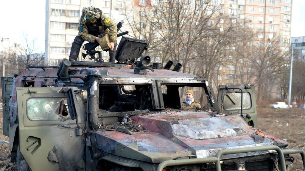 An Ukrainian Territorial Defence fighter examines a destroyed Russian infantry mobility vehicle GAZ Tigr after the fight in Kharkiv