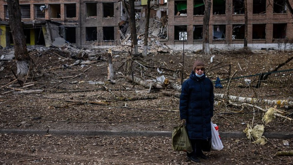 A woman stands in front of a destroyed building after a Russian missile attack in the town of Vasylkiv, near Kyiv, on February 27, 2022
