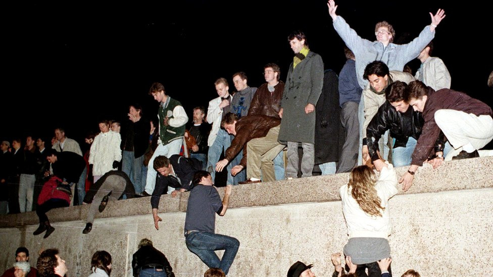 East German citizens climb the Berlin wall at the Brandenburg gate after the opening of the East German border was announced in Berlin on 9 November 1989