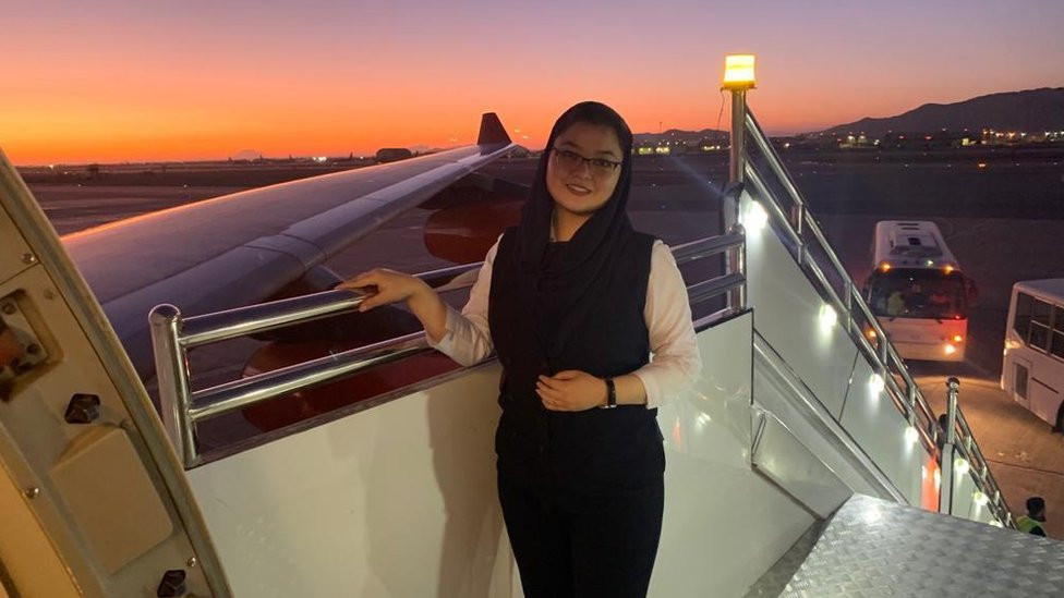 Fazila Haidari stands on the steps at the door of an aeroplane