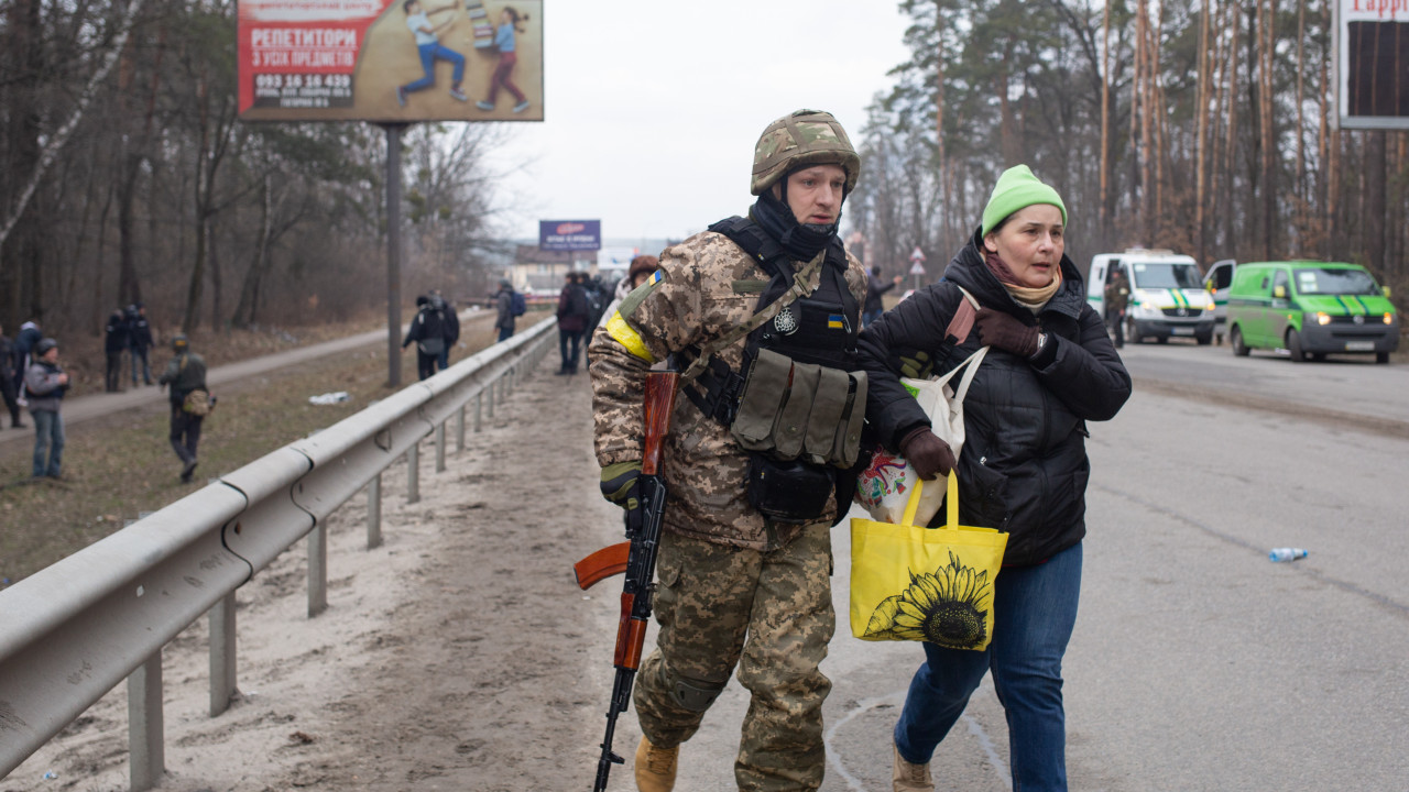 A Ukrainian soldier helps a civilian woman in Kyiv
