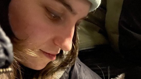 Yustyna Dusan on her phone while holding a cat