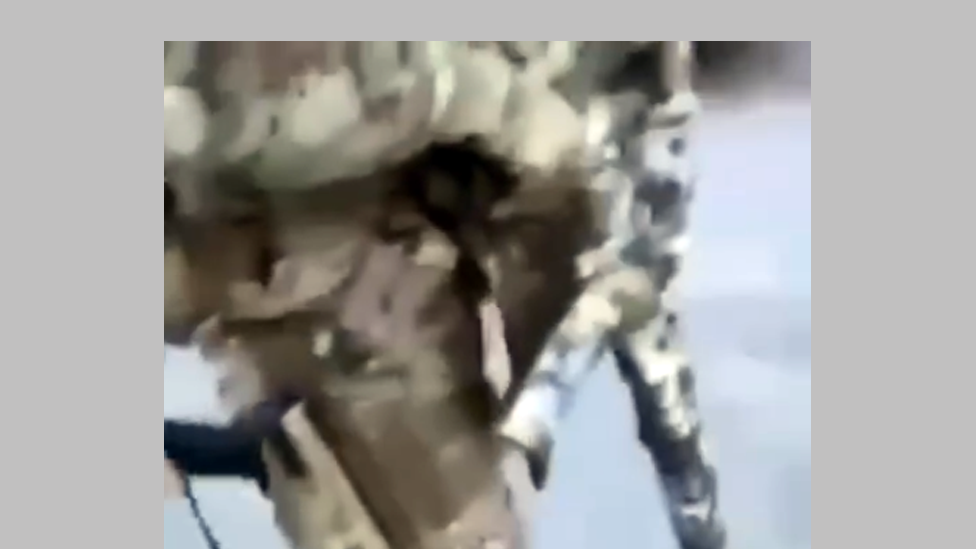 Still from the video showing a soldier carrying a camouflaged assault weapon