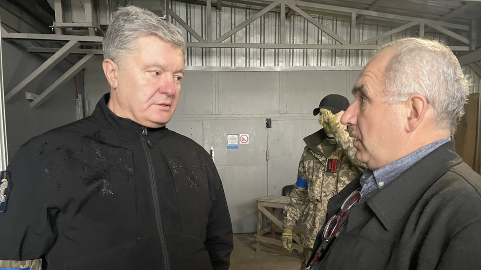 Petro Poroshenko, Ukraine's former president, in a weatherproof jacket, speaks seriously to a man inside the Chernobyl plant