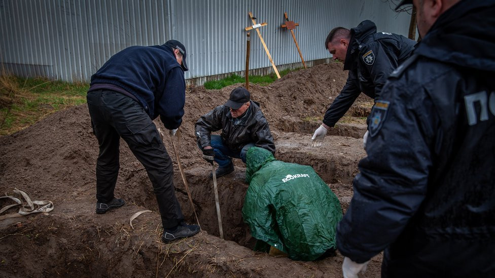 Gennadiy, a resident who buried his neighbours, helps to bring them up from their graves.