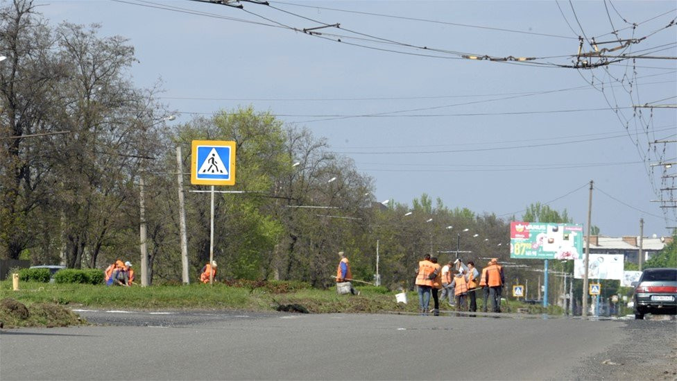 Workers clear weeds in Bakhmut