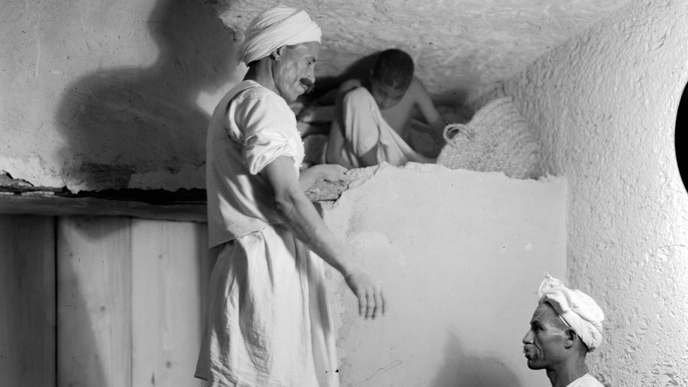Egyptian foremen and a boy dismantle a partition wall to open up Tutankhamun's burial chamber