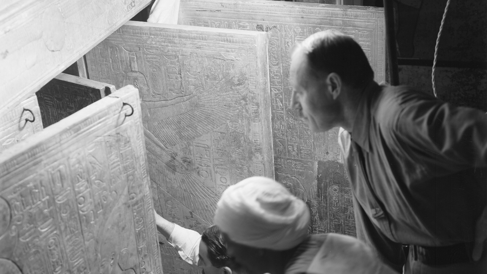 Howard Carter, his assistant Arthur Callender and an unidentified Egyptian open the doors of a gilded shrine inside Tutankhamun's tomb