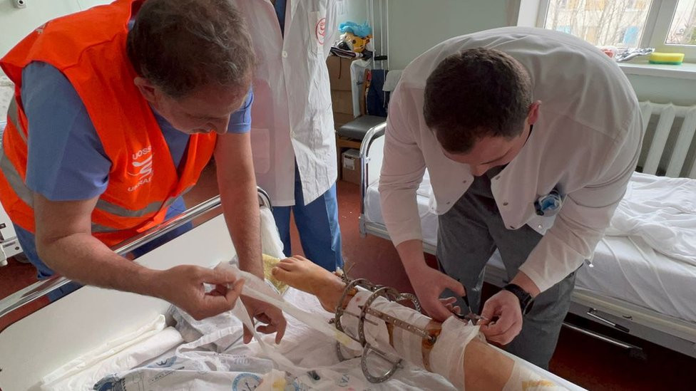 Dr Monzer Jaži i još jedan doktor previjaju pacijentovu nogu