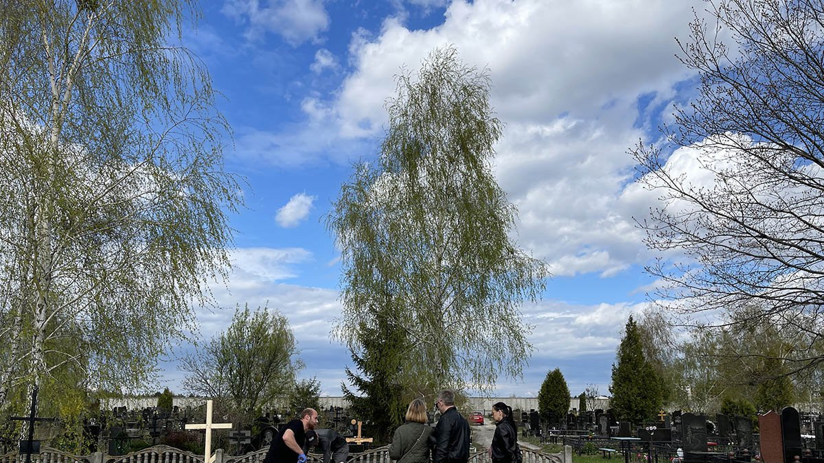 family in Bucha cemetery - a fresh grave is being dug