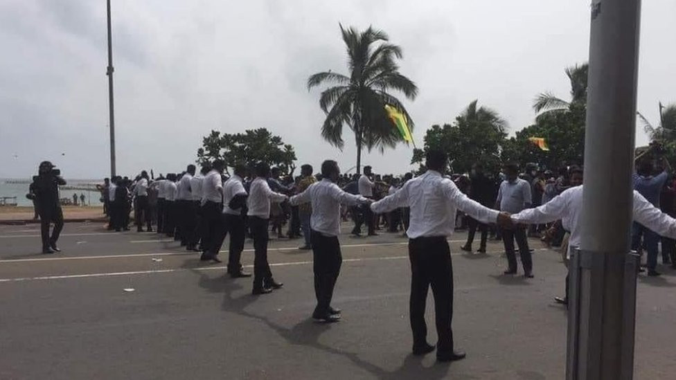 Lawyers s]holding hands to make a human chain to protect protesters at the main protest site in Colombo