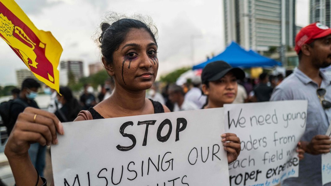 A woman holds a placard saying 'Stop misusing our rights', standing among protesters