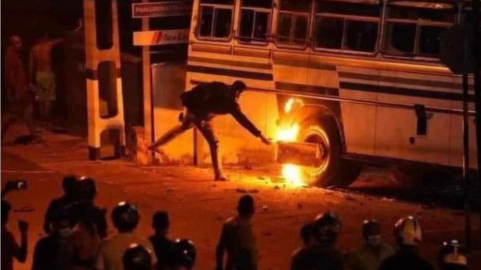 A man ignites flames on the wheel of a bus