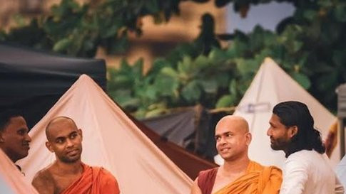 Buddhist monks stand between tents with protesters