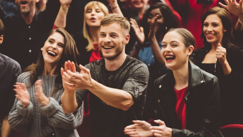 Group of excited people clapping hands in the theatre