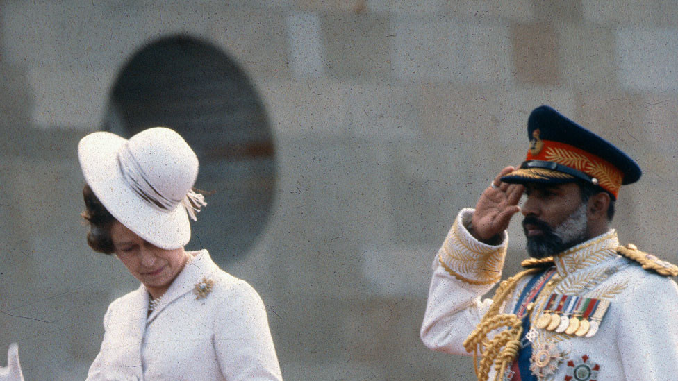 Queen Elizabeth ll nearly loses her hat in the wind as she attends a welcoming ceremony with Sultan Qaboos of Oman on 28 February 1979 in Muscat. Oman.