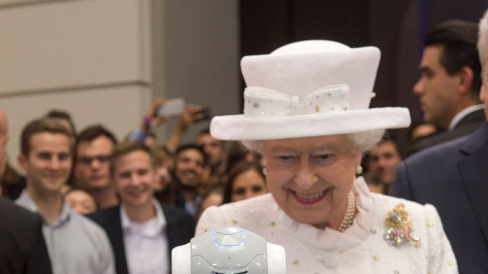Queen in white hat looking at robot