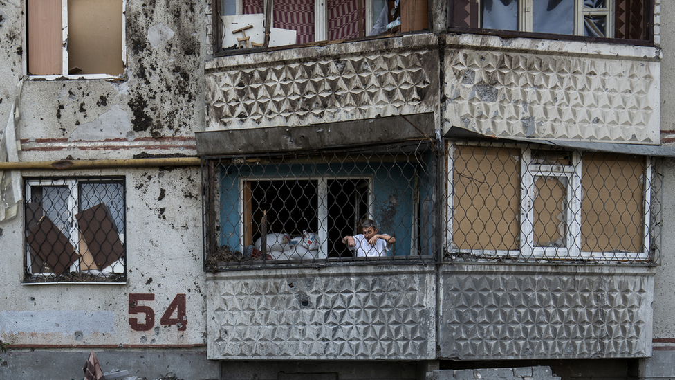 A resident of Saltivka building 54 looks down from his balcony at a shell crater beneath. "This is the Russian world," he said