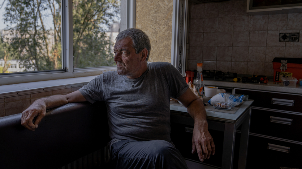 Valeriy Ivanovych looks out from his apartment window. Only two people are left among the 18 apartments in this side of the building