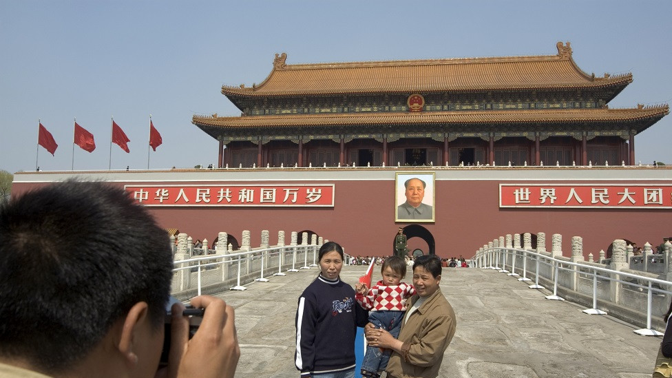 Chinese tourists pose for pictures in front of Mao's portrait at Gate of Heavenly Peace in Tianenman Square