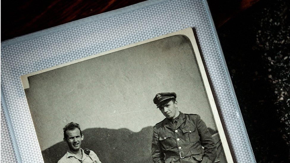 Black and white photo pf two men standing - one in uniform