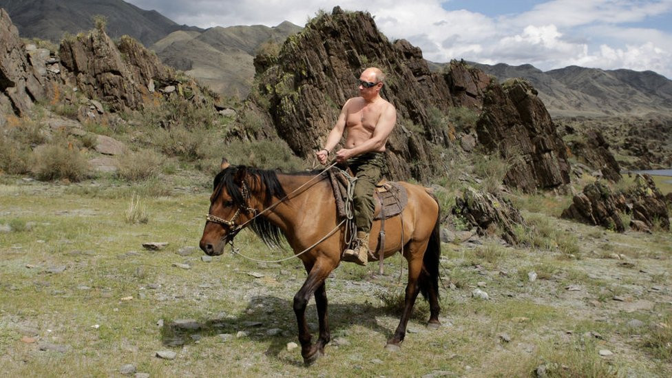 Vladimir Putin, bare-chested, riding a horse