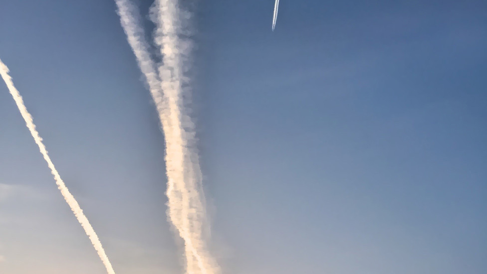 Aircraft vapour trails of scheduled services flying into Heathrow over the former BBC Monitoring building in Reading
