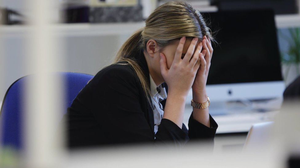 Female office worker with head in hands