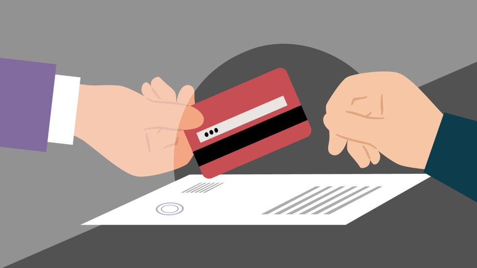 Čovek predaje karticu službeniku banke preko pulta