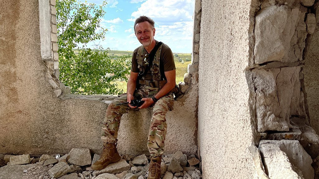Serhii sits in a ruined building