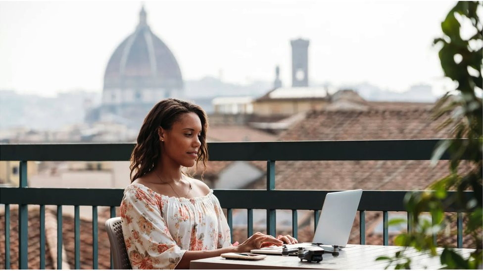 Woman sits outside on a laptop