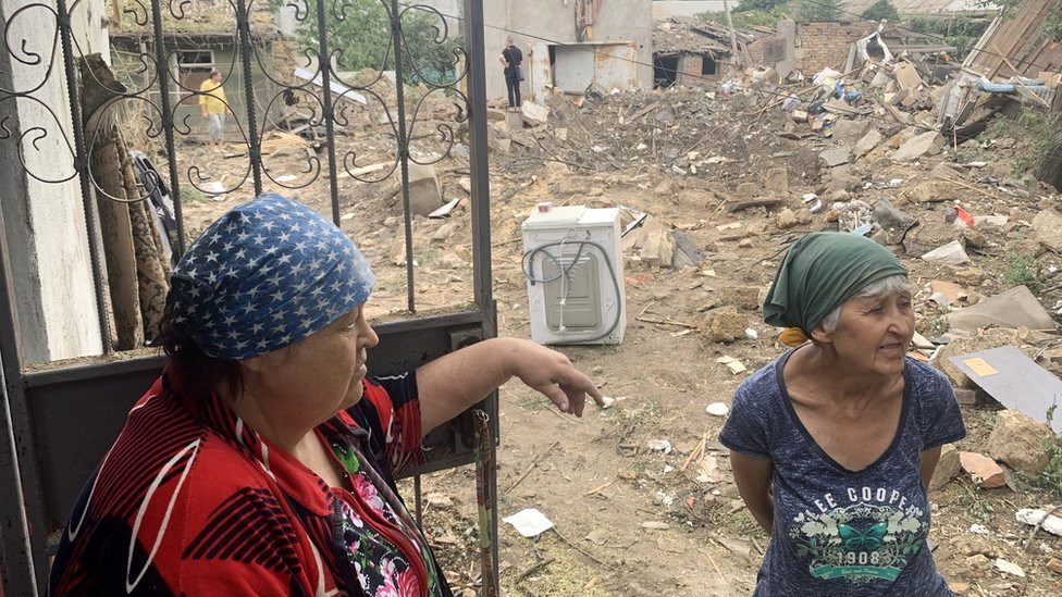 Svetlana Kharlanova (left), 67, stands in front of her cottage near a deep crater left by a missile in her yard in Mykolaiv