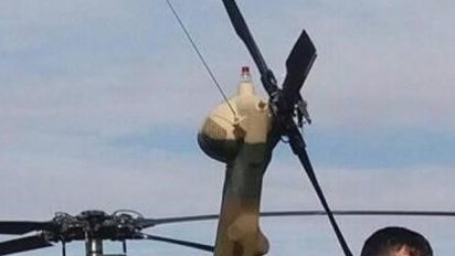 Momand standing n front of his helicopter