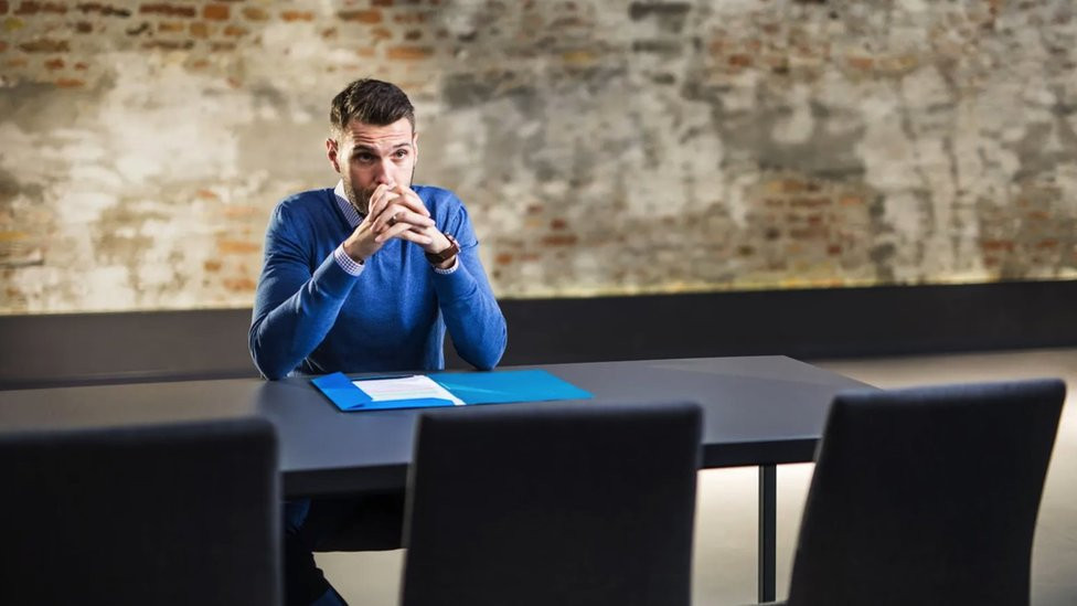 Man sits at desk thinking