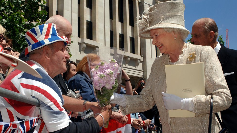 Queen Elizabeth II accepts flowers from Royal fan Terry Hutt outside at St Paul's Cathedral, London, after a service of thanksgiving in honour of her 80th birthday