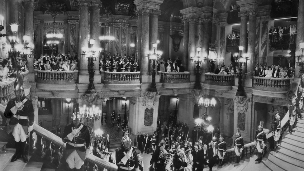 Queen Elizabeth II, ascending the Grand Staircase at the Opera in Paris during a state visit to the French capital, 8 April 1957. The image is a montage of 15 separate pictures.